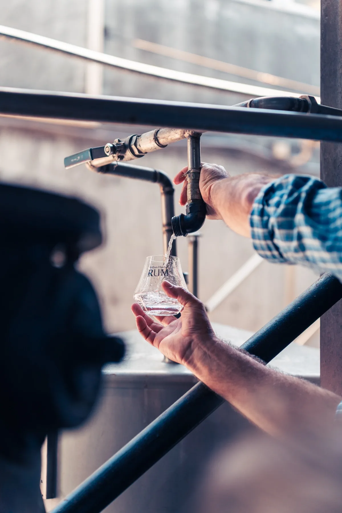 Hands drawing rum from a spigot into a tasting glass